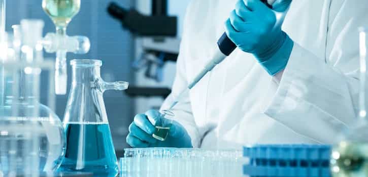 Empleados de un laboratorio trabajando y protegidos frente a los riesgos biológicos